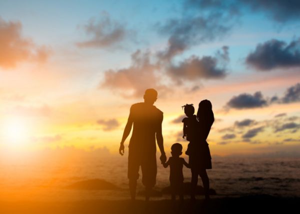 Family of four standing in front of a sun set